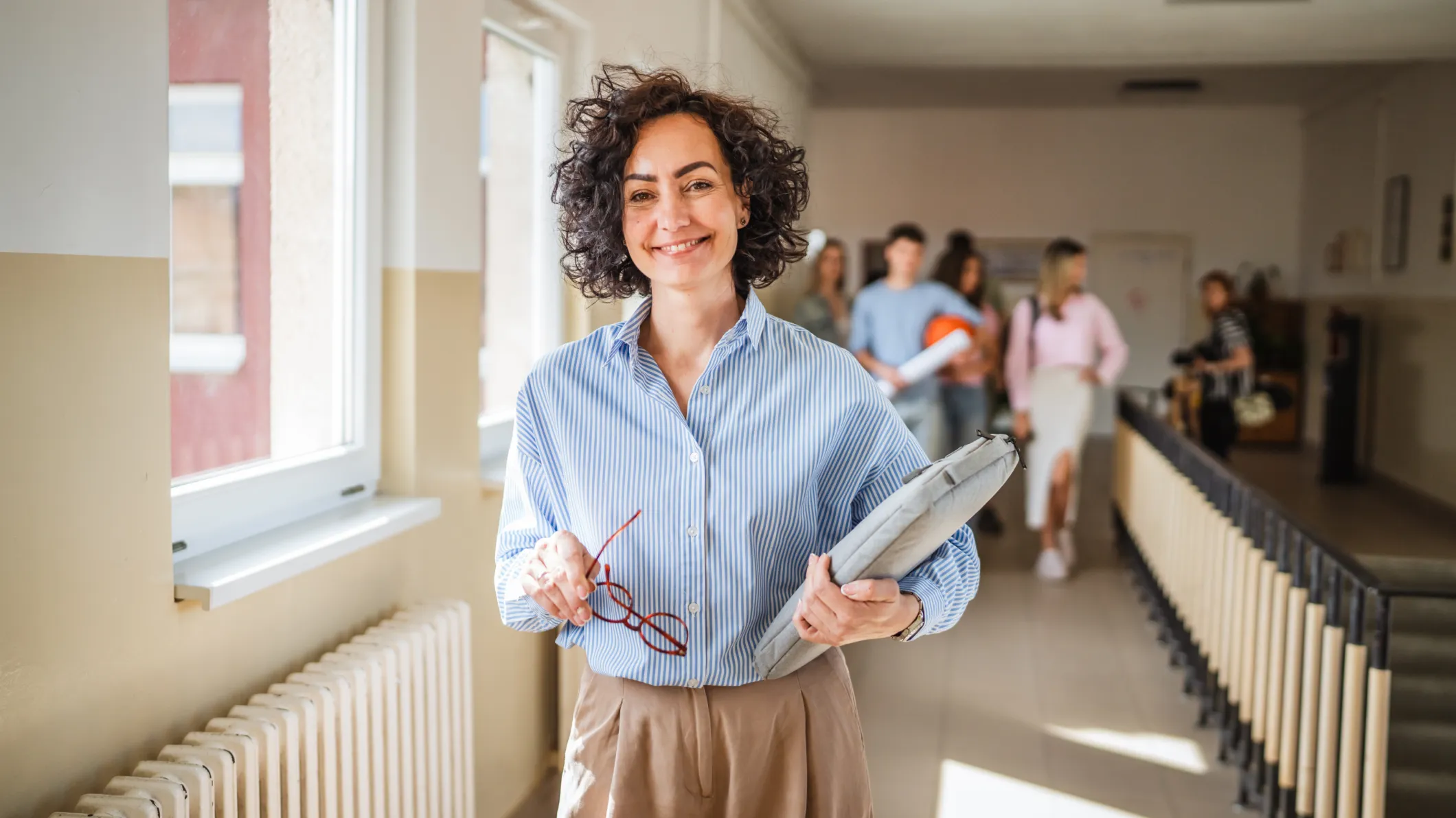 Happy female teacher walking in corridor of school